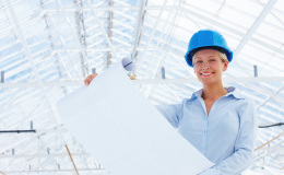 Happy lady architect holding blueprint at construction site