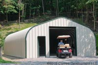 outer view of a tan steel building with green trim storing a golf cart