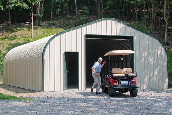 a metal building with green trim used for storing a golf cart