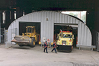 round top steel building shown with city trucks parked inside 