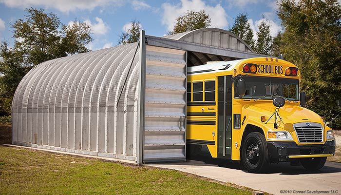 metal arch style building with traditional color. Yellow school bus pictured sticking out 