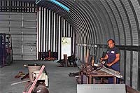 a man is standing at a bench in his steel building workshop